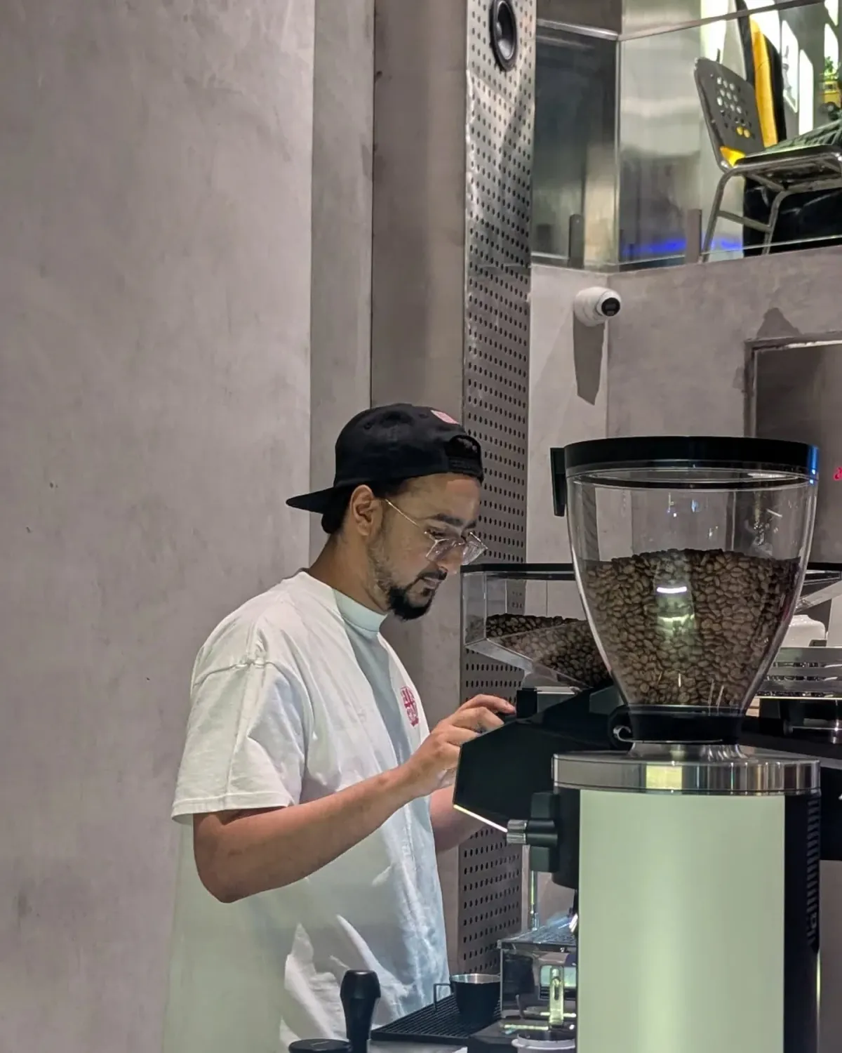 Ahmed Hussain dialling in an espresso grinder full of fresh coffee beans