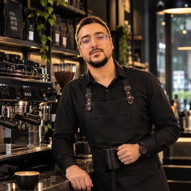 Ahmed Hussain, coffee consultant in Lahore, at the espresso bar with a milk pitcher