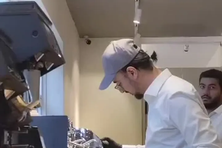 Ahmed Hussain weighing an espresso shot at a commercial espresso machine