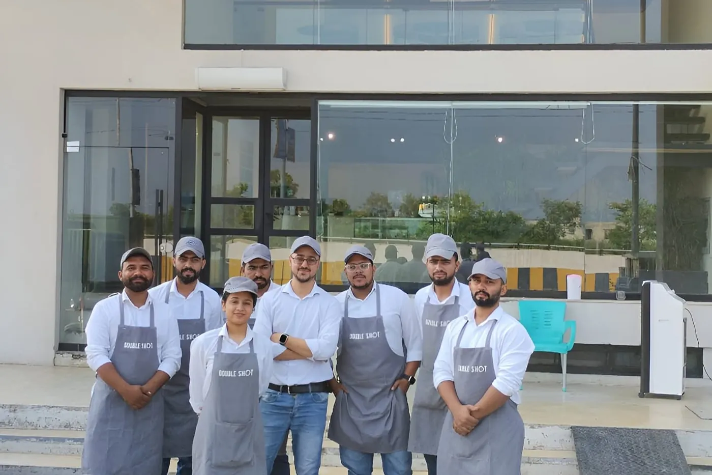 A café team in aprons outside a newly opened coffee shop in Pakistan